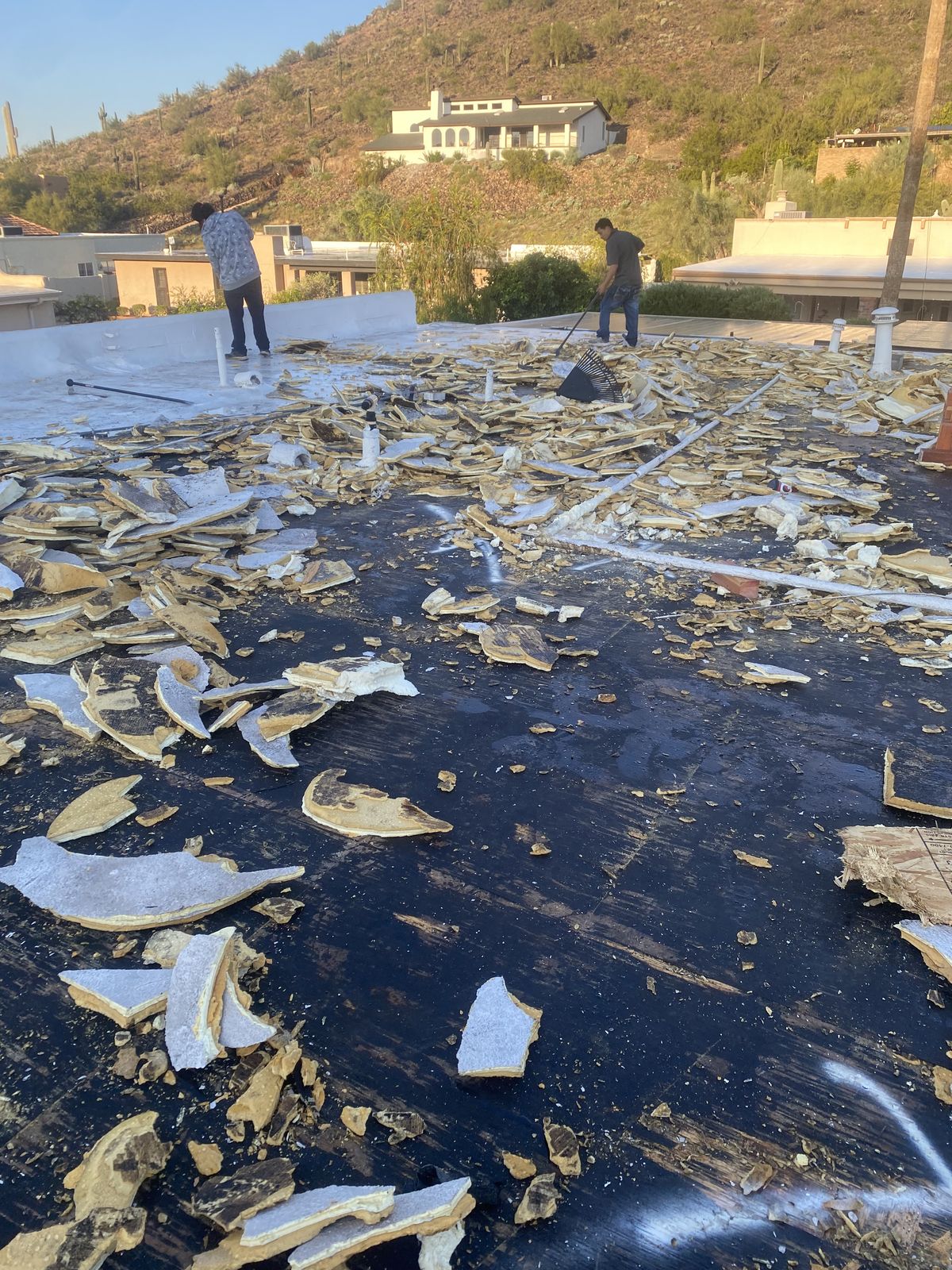Flat roof tear-off in progress, old roofing broken up across the deck