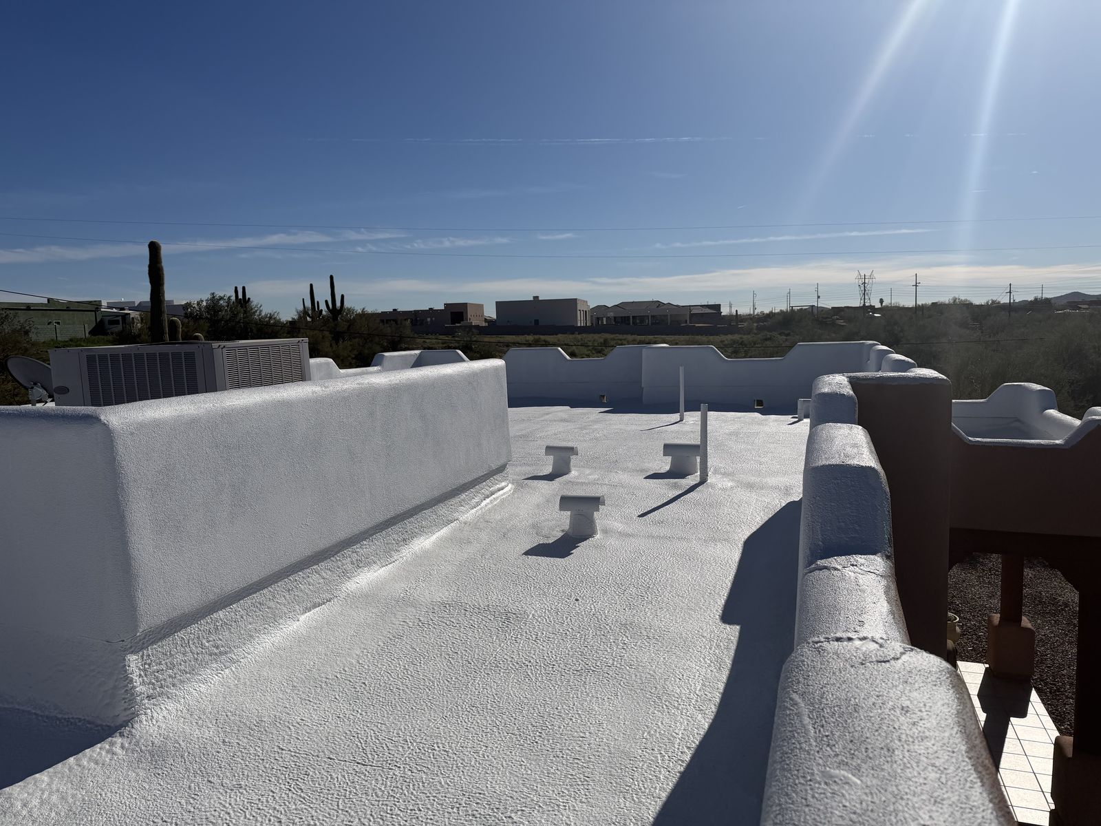 Recoated flat roof with parapet walls, finished in a bright white coating