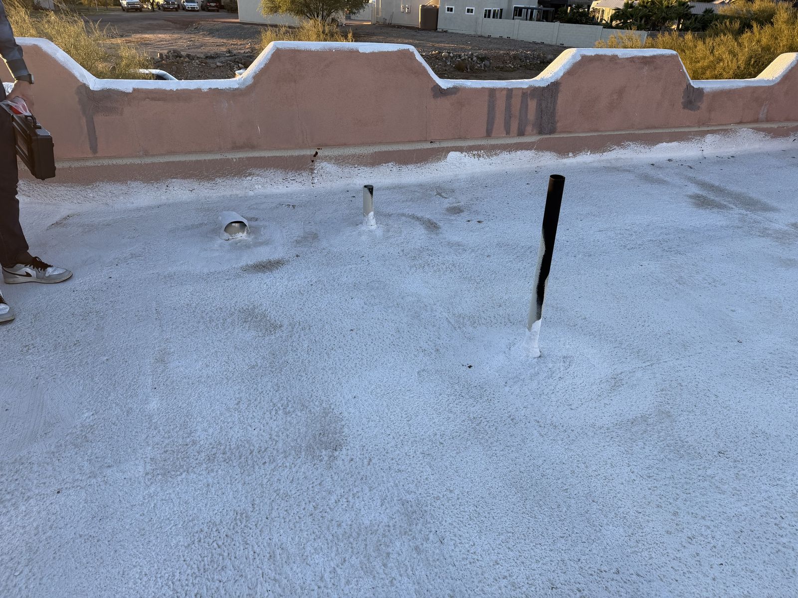 Flat roof parapet before the recoat, coating dirty and failing along the wall