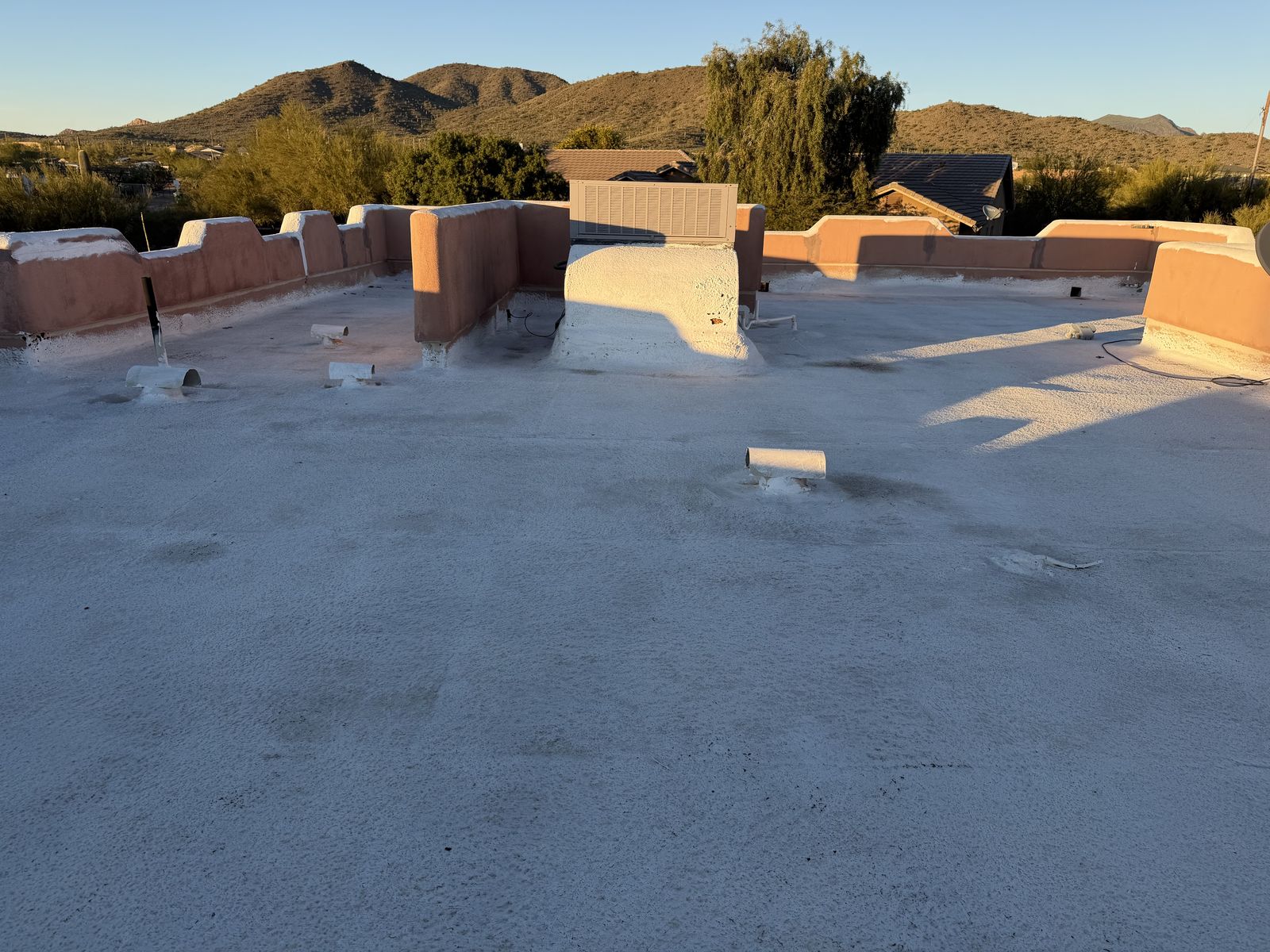 Flat roof before the recoat, the old coating worn through and patched around the rooftop units