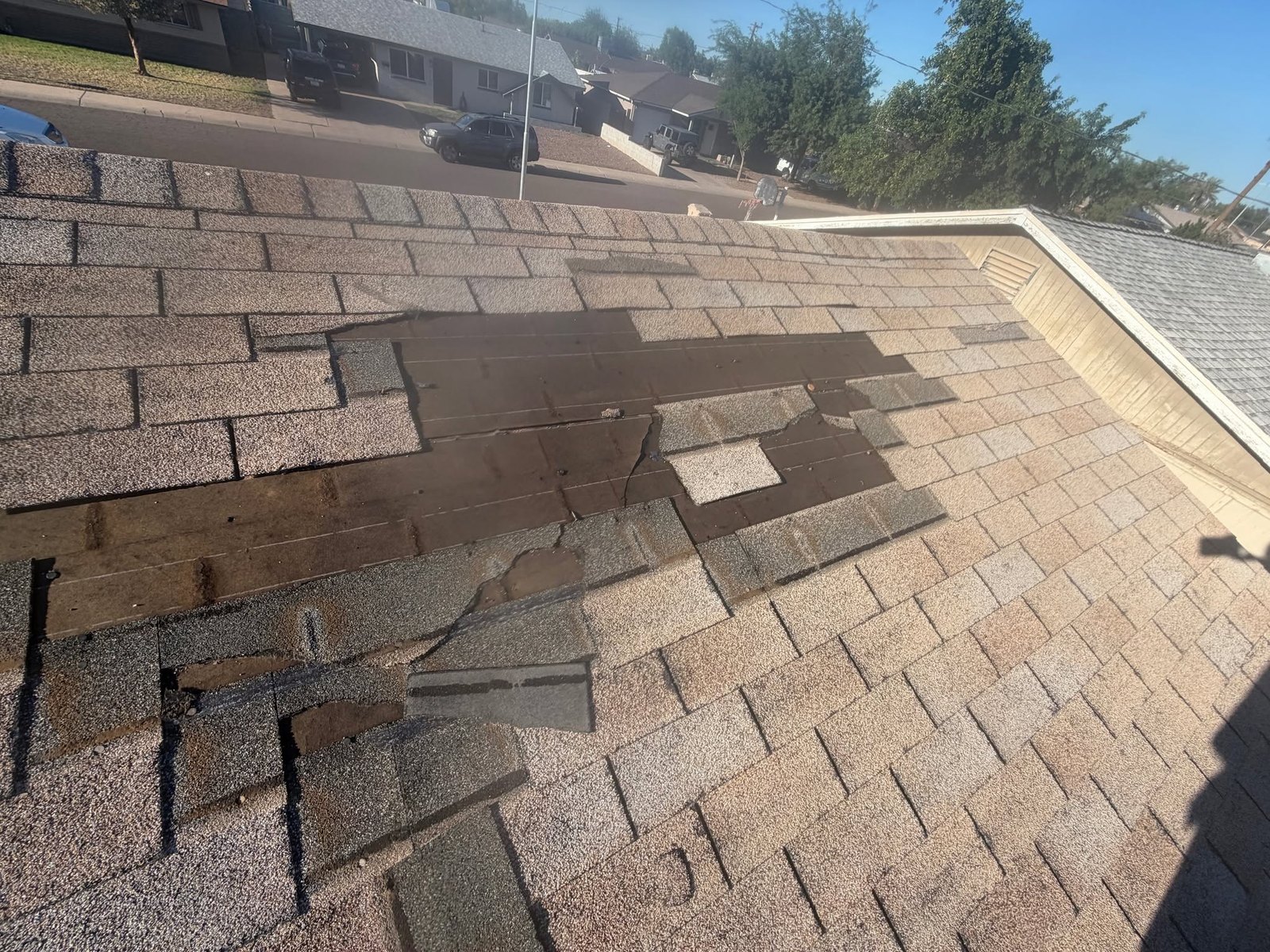 Old shingle roof with whole sections blown off down to the bare deck