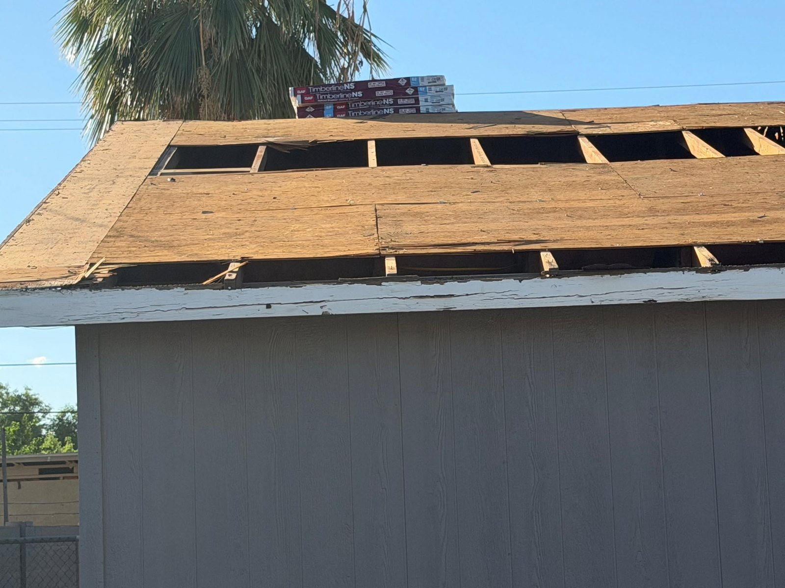 Tear-off down to the rafters with the decking opened up and new shingle bundles staged on the ridge
