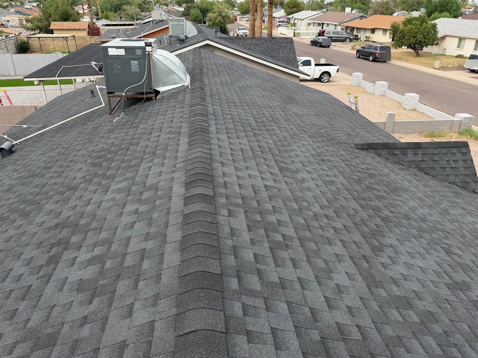 Finished architectural shingle roof along the ridge, rooftop unit flashed in