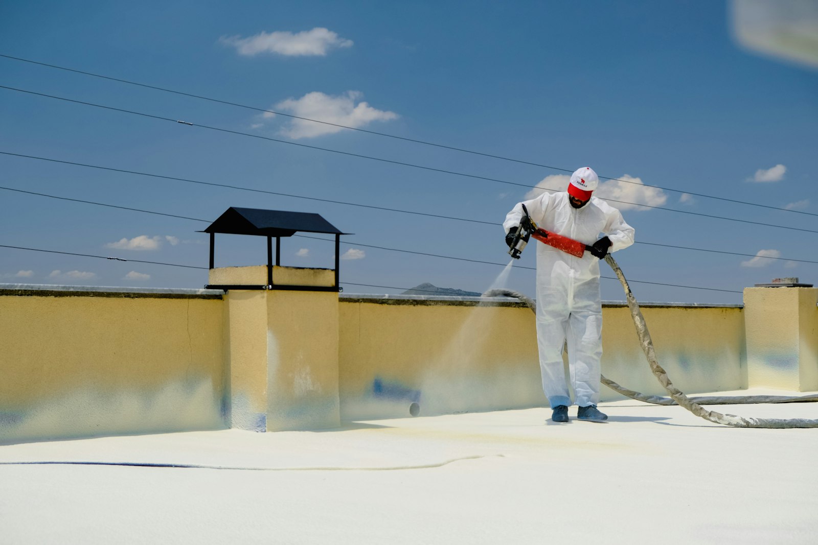 A flat roof being spray-coated white, parapet walls around it