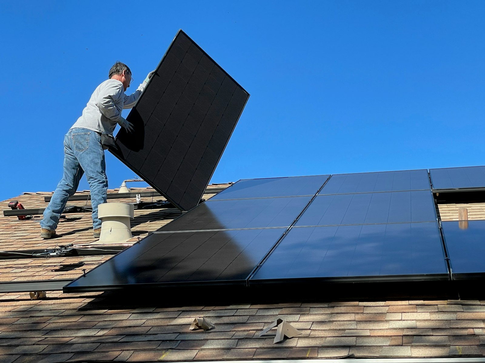 Solar panels being set on a shingle roof