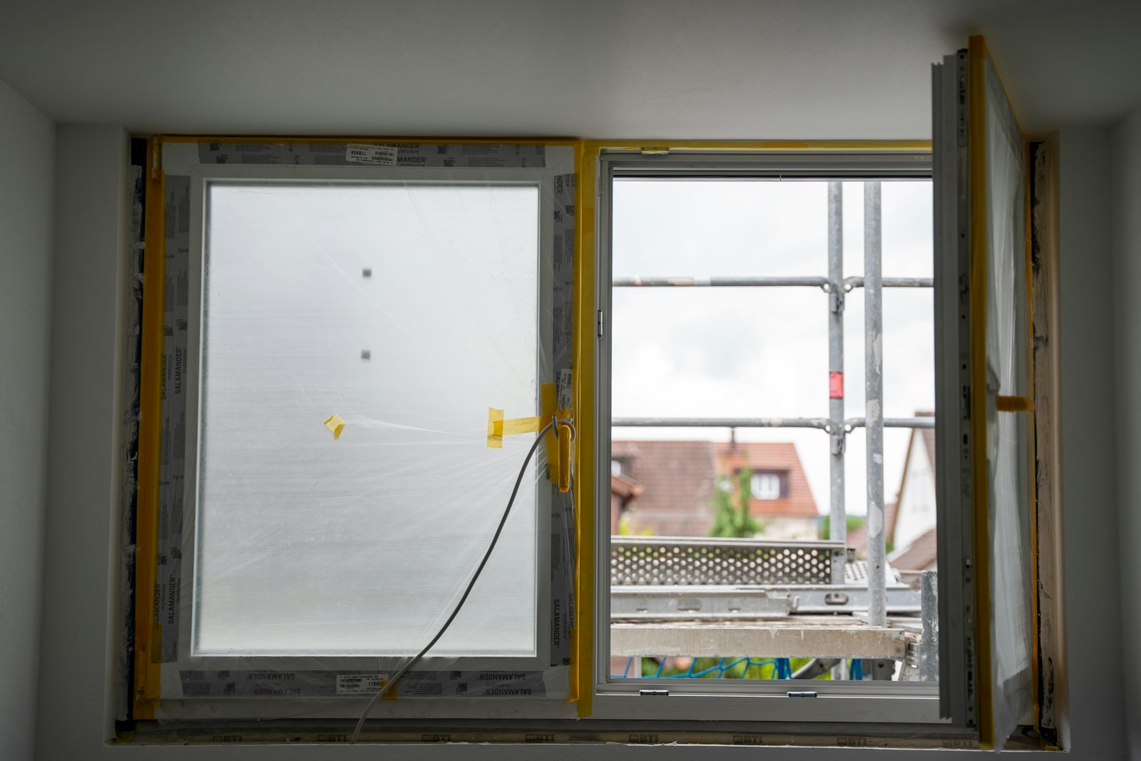 A window frame mid-installation, protective film still on the glass